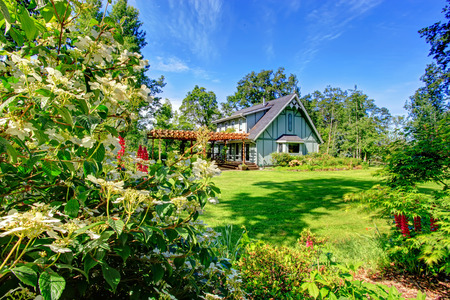 Mint color farmhouse with attached pergola and beautiful flowerbedの写真素材
