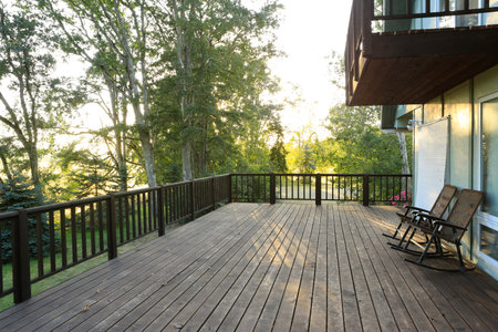 Large deck with chairs overlooking summer countryside forest