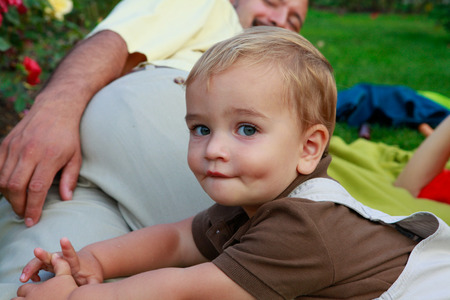 Happy Baby boy and parents are playing in the park during sunset.の写真素材