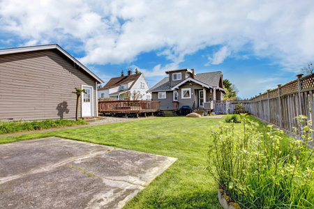 Fenced backyard with green lawn and deck 