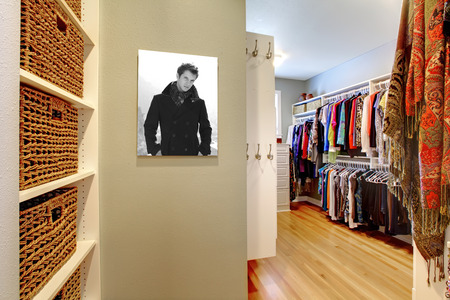 Spacious walk-in closet with shelves filled with wicker baskets and hanging clothesの写真素材