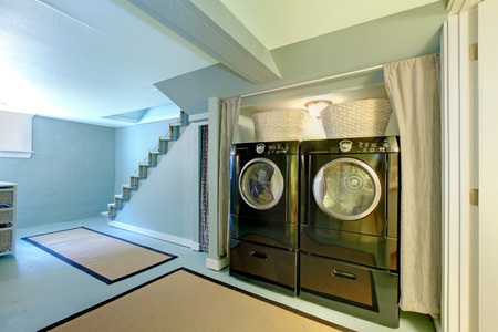 Blue basement laundry room with black washe and dryer.の写真素材