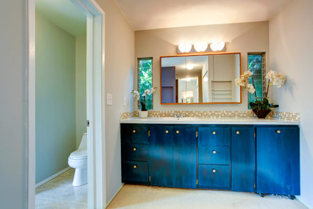 View of light tones bathroom with wooden blue vanity cabinet decorated with white flowersの写真素材