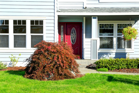 Classic american house with entrance porch and red door. View of front yard landscapeの写真素材