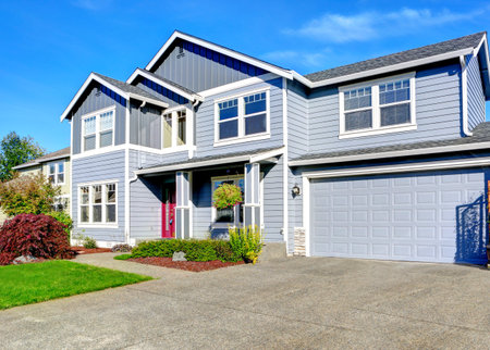 Light blue two story house with column entrance porch, garage and driveway view