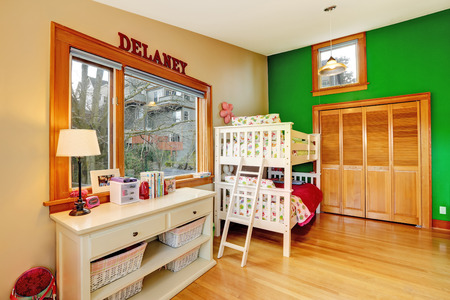 Bright kids room with contrast green wall. Furnished with loft bed and cabinet with storage basketsの写真素材