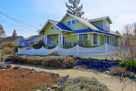 Light green house with column entrance porch and front yard with white fenceの写真素材