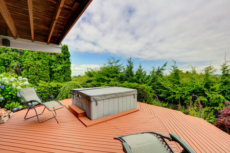 Cozy covered deck with hot tub and chairs. Deck has a beautiful nature view