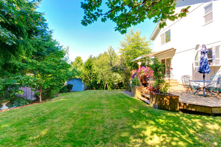 Walkout deck with patio table and umbrella overlooking backyard gaden