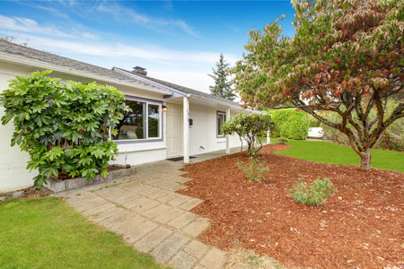 Simple house exterior in white color. Front yard landscape with sawdust and lawn.