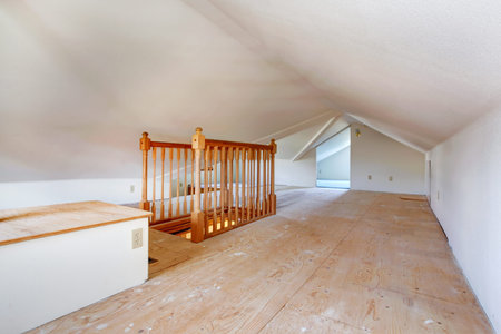 Upper empty room with low vaulted ceiling, old wooden floor and staircase