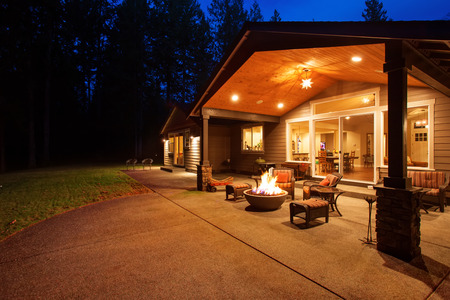 Large back yard with grass and covered patio with firepit.の写真素材