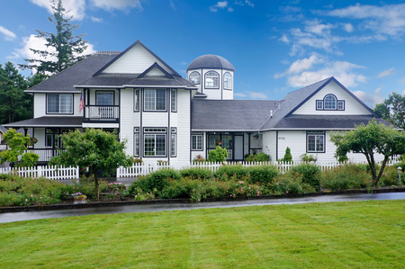 Large white house with blue trim and grass filled yard.の写真素材