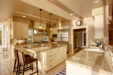 Large luxury kitchen room in beige colors with granite counter tops, stainless steel fridge and tile...