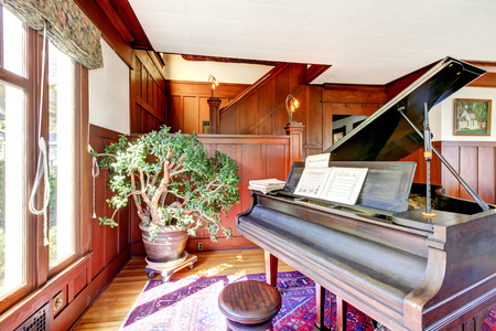 Bright living room with wooden panel trim walls and grand piano. Northwest, USAの写真素材