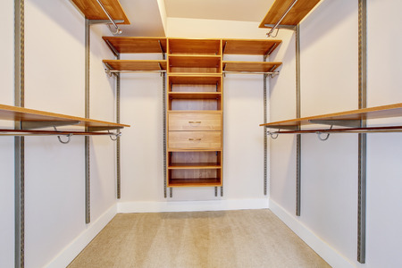 Bright empty walk-in closet with wood shelves, beige carpet floor. Northwest, USAの写真素材