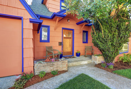 Coral exterior American house with blue trim. Concrete floor porch with wooden chairs. Northwest, USAの写真素材