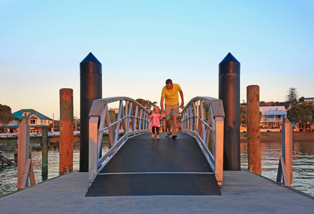 Happy young father with his little daughter run across the small bridge early in the morning. Russel, NEw Zealandの写真素材