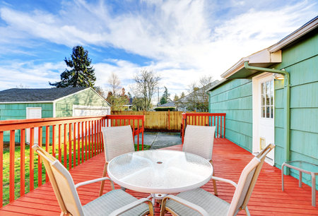 Red wooden walkout deck with table set, American bungalow house exterior. Northwest, USA