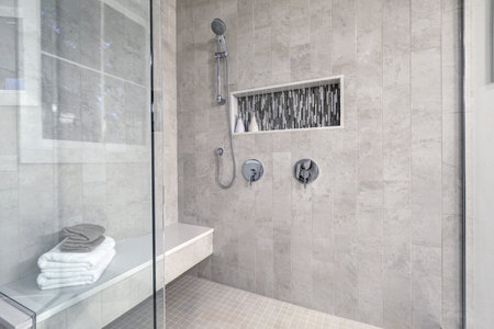 Glass walk-in shower with gray subway tiled surround accented with mosaic tile strip in wall niche of brand new home bathroom. Northwest, USAの写真素材