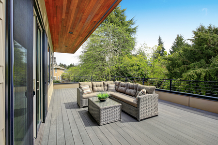 Contemporary deck features a modern wicker sectional accented with gray seat cushions facing a wicker coffee table. Northwest, USAの写真素材