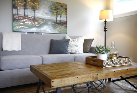 Family room interior with close up of a wood and metal frame coffee table next to a gray sofa with pillows.の写真素材
