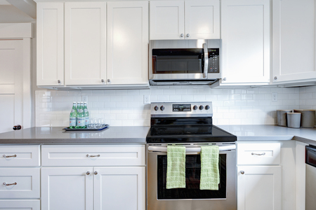 White and gray kitchen room with modern stainless steel appliances,  quartz countertops and subway tile backsplash.の写真素材