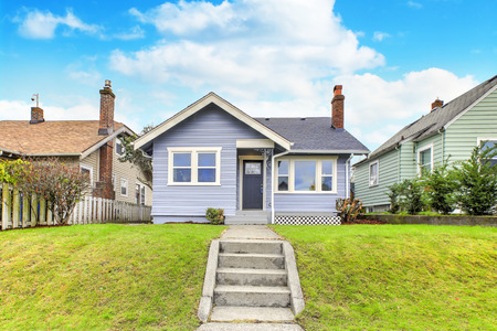 Charming blue home exterior with green grass in the front yard.の写真素材
