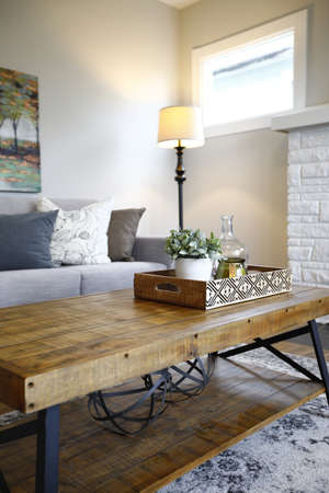 Family room interior with close up of a wood and metal frame coffee table next to a gray sofa with pillows.の写真素材