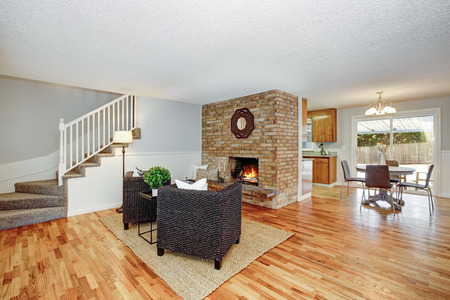 Spacious light filled living room interior accented with brick fireplace and wicker chairs.の写真素材