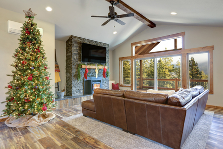 Christmas room interior design. Living space features beamed ceiling, stone fireplace and decorated Christmas tree.の写真素材