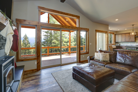 Living room interior with stone fireplace, leather sofa and view of spacious deck.の写真素材