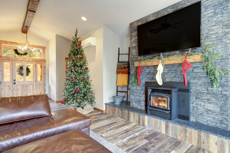 Nicely decorated home interior for Christmas. Living area boasts grey stone fireplace with stockings, rustic wood floor and high vaulted ceiling.の写真素材