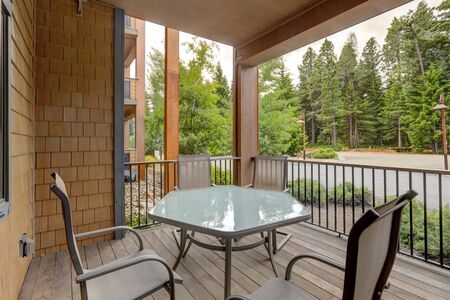 Condo style luxury vacation living in apartment building balcony with pine trees views and table with four chairs.の写真素材