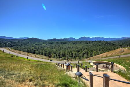Beautiful open valley with Cascade mountains and pine trees and large lodge with deck.の写真素材