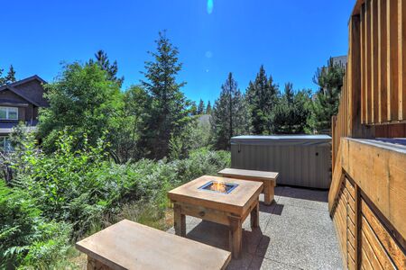 Small but open to greenery back yard space with fire and hot tub and wooden deckの写真素材