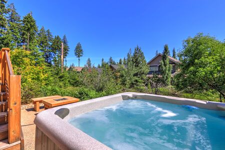 Small but open to greenery back yard space with fire and hot tub and wooden deckの写真素材