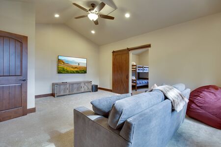 Large family game fun room with tall vaulted ceiling and large double windows, beautiful natural tones furnitutre and large TV. Ceiling fan and doors open to other rooms.の写真素材