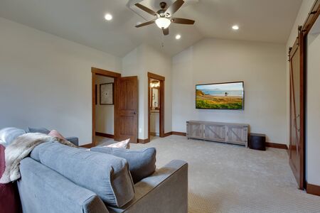 Large family game fun room with tall vaulted ceiling and large double windows, beautiful natural tones furnitutre and large TV. Ceiling fan and doors open to other rooms.の写真素材