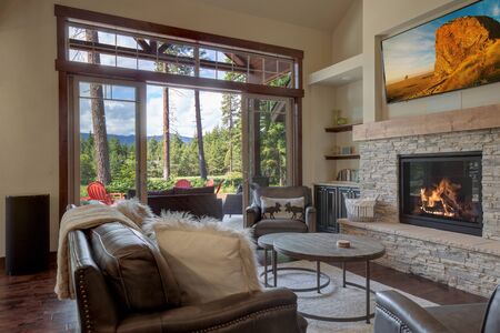 An absolute beautiful luxury living room with huge vaulted  ceiling, fire place, harwood floor, amazing furniture, and lots of windows and doors. Solid wood rustic modern dining room table.の写真素材