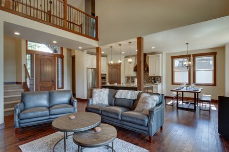 An absolute beautiful luxury living room with huge vaulted  ceiling, fire place, harwood floor, amazing furniture, and lots of windows and doors. Solid wood rustic modern dining room table. open concept.の写真素材