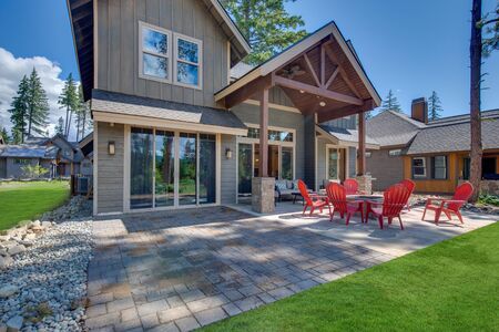 Huge open to nature Back yard with fire pit , amazing patio and red chairs near newly bild luxury real estate home with forest biew and green grass.の写真素材