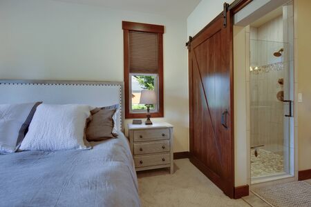 Beautiful large luxury new bedroom with great design, beige, grey and white tones, TV bove dresser, rich wooden doors, window blinds and grey carpet. Cozy and practicle. Expensive furniture. Doors open to back yard patio.の写真素材