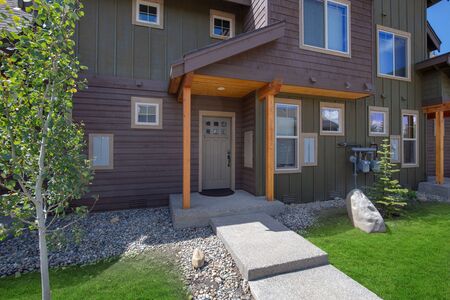 Newly build modern and rustic home from exterior in natural brown and grey colors with walkways, green grass and natural stone.  Blue sky and sunny day. American new archtecture.の写真素材