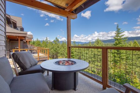 Amazing balcony patio with fire pit and forest and mountains view. Dream come true home exterior. New American architecture. Comfortable and beautiful home details.の写真素材