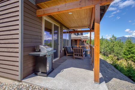 Porch covered small balcony with grill and some furniture overlooking the forestの写真素材