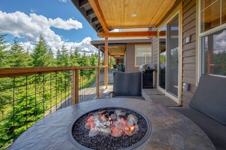 Amazing balcony patio with fire pit and forest and mountains view. Dream come true home exterior. New American architecture. Comfortable and beautiful home details.の写真素材