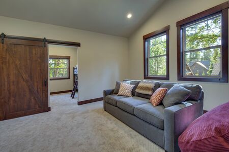 Large family game fun room with tall vaulted ceiling and large double windows, beautiful natural tones furnitutre and large TV. Ceiling fan and doors open to other rooms.の写真素材