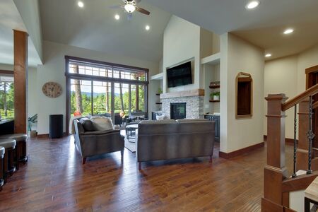 An absolute beautiful luxury living room with huge vaulted  ceiling, fire place, harwood floor, amazing furniture, and lots of windows and doors. Solid wood rustic modern dining room table. open concept.の写真素材