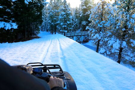 Man riding snowmobile or fourwheeler on the country side trail near water canal.の写真素材